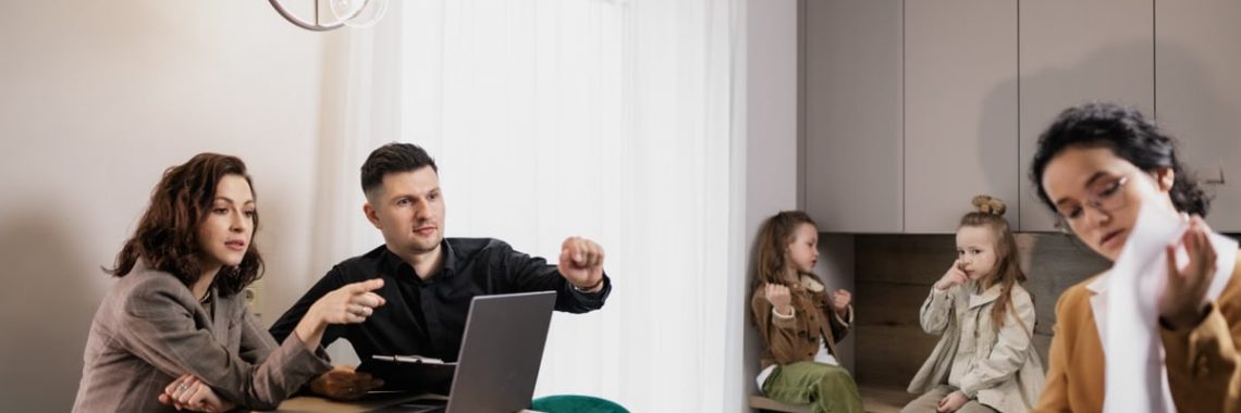 Family discussing real estate purchase inside home with agent and children present.