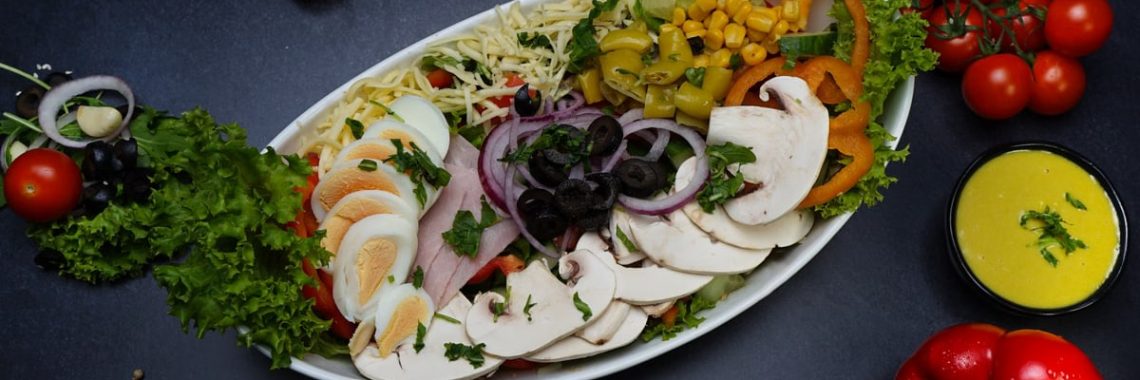 Vibrant garden salad with mixed vegetables, eggs, and dressing on a dark background.
